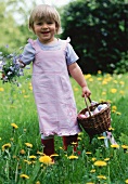A little girl holding flowers and a basket of Easter eggs