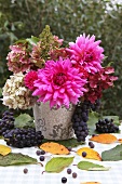 An autumnal bouquet of flowers and red grapes on a garden table