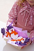 Mädchen hält Schachtel mit Schneemann-Baumanhängern (aus Salzteig)