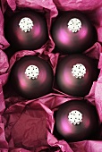 Five purple Christmas baubles in a box