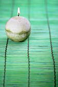 Round candle on green bamboo mat