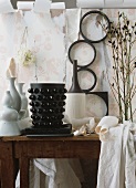 Black and white vases on table in front of torn wallpaper
