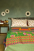 Bed with a printed bedspread and framed mirrors on a wall