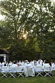 A party in a garden with people sat at white tables
