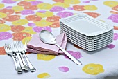 Rectangular plates, spoon, serviettes and fork on a colorful tablecloth
