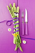 Green asparagus tied with a bow on a purple wooden surface