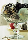 A glass bowl full of Christmas baubles