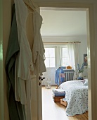 Blick vom Badezimmer in ein helles Schlafzimmer mit stummem Diener und großem Doppelbett