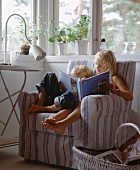 Two children sitting in an armchair reading a book