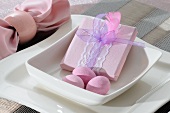 A present wrapped in pink with sweet Easter eggs in a bowl