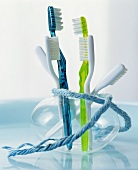 Coloured toothbrushes in a glass vase wrapped with a piece of string