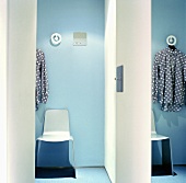 A plastic chair in front of a light blue wall in a hallway in an apartment