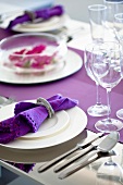 A place setting with a purple napkin in a napkin ring