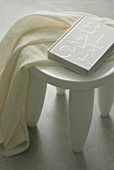 A white stool with a linen cloths and a book