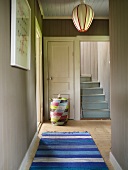 Bright gray foyer in a country home with blue carpet runners and bright blue wooden stairs