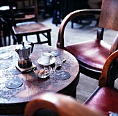 Espressokanne, Kaffeetasse, brauner Zucker & Bierdeckel auf rundem Tisch in einem Café