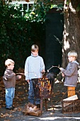 Three boys toasting marshmallows over an open fire