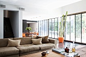 A spacious living room with a window bank and a brown sofa with cushions