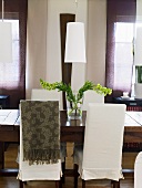 An elegant dining room - covered chairs at a wooden table and white lampshades