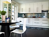 Offene Küche - Blick auf weiße Einbauküche mit Edelstahlgriffleisten