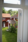 Blick durch Fenster auf Holzhaus mit überdachten Hauseingang