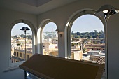 Stehlampen im Raum mit Rundbogenfenster und Blick auf eine südländische Stadt