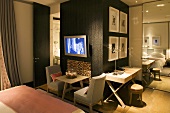 TV in a bedroom with furniture around a room divider with chairs and tables