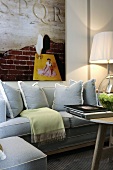 Light gray sofa and picture in front of a wall and a table lamp with a pleated shade