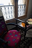 Upholstered chair and black side table in front of a window with parapet grid