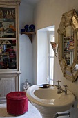 Corner of a bathroom -- pedestal sink with mirror and pink ottoman