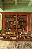 Mahogany bookcase against green wall
