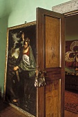 Offenstehende Zimmertür und Gemälde an grüner Wand lehnend