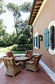 Korbstühle auf Terrasse mit Fischgrätmuster auf Boden vor Fassade einer Mediterraner Villa