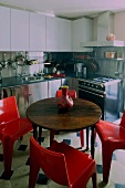 Runder Holztisch mit roten Kunststoffstühlen in Einbauküche