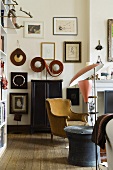 A corner of a living room in a period building - a mix of furniture styles and a collection of pictures on the wall