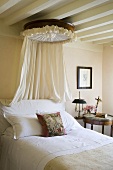 A bed room in a country house with a white wood beams and a canopy over the bed