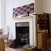 A white fireplace with cladding and a metal stand hung with ethnic cloths