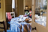 A view through an open door onto a breakfast table in the kitchen of a country house