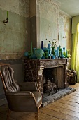Antiker Ledersessel neben Kamin mit blau grüner Vasensammlung auf Sims im Vintage Wohnraum