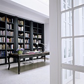 Dunkelgraues Bücherregal und antiker Schreibtisch im minimalistischen Raum