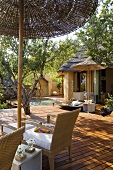 Wicker furniture under a bamboo umbrella on a wooden terrace of a South African home