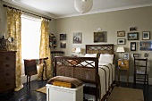 Antique double bed in front of a wall in gray tones with a collection of pictures