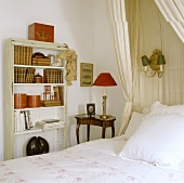 Antique night stands with lamps and red shades next to white shelves in the corner of a bedroom