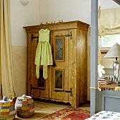 A girl's party dress hanging on an antique rustic wardrobe in a child's bedroom