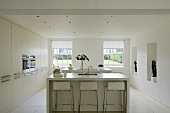 A free-standing kitchen counter with bar stools in the centre of a white kitchen