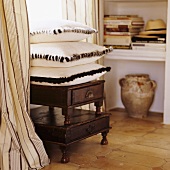 A stack of cushions with a fur border on a rustic wooden stool