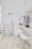 Designer chairs at a white workbench against a wall
