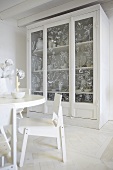 White - a dining area and a glass-fronted cupboard
