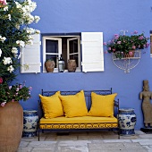 Yellow sofa cushions on a decorative metal frame in front of a blue wall
