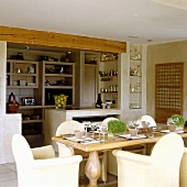 A table laid with armchairs and view into the open-plan kitchen